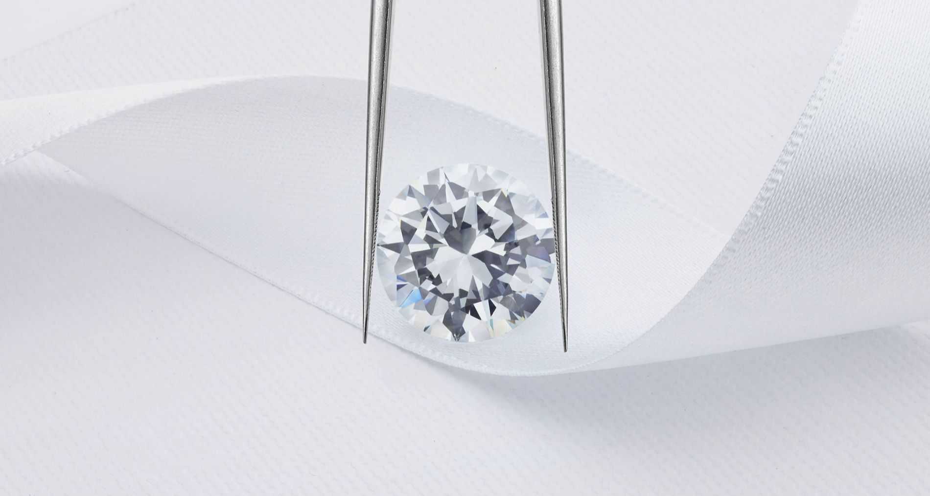 Loose Lab Diamond held by diamond tweezers being analyzed by a gemologist.