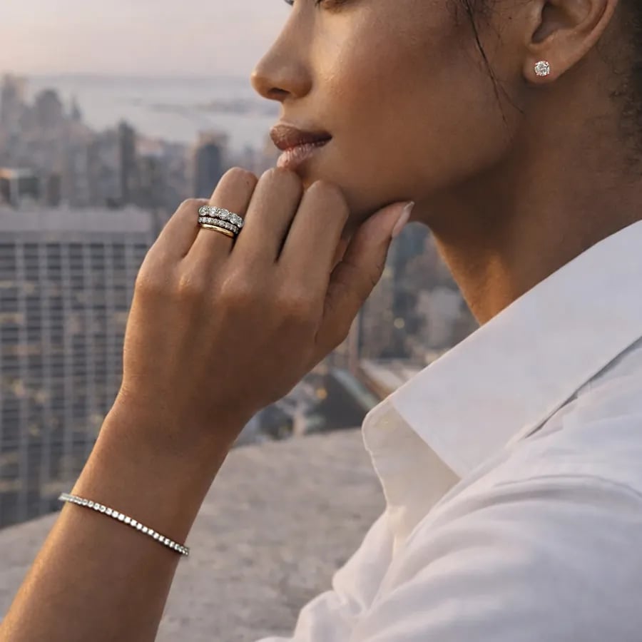a woman on a balcony viewing the new york city skyline wearing a tennis bracelet and an engagement ring and wedding ring